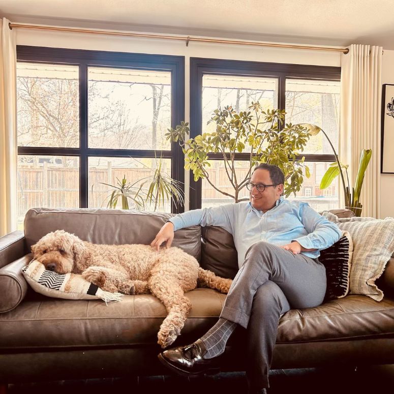 Josh Salmon and a dog on the couch in home.