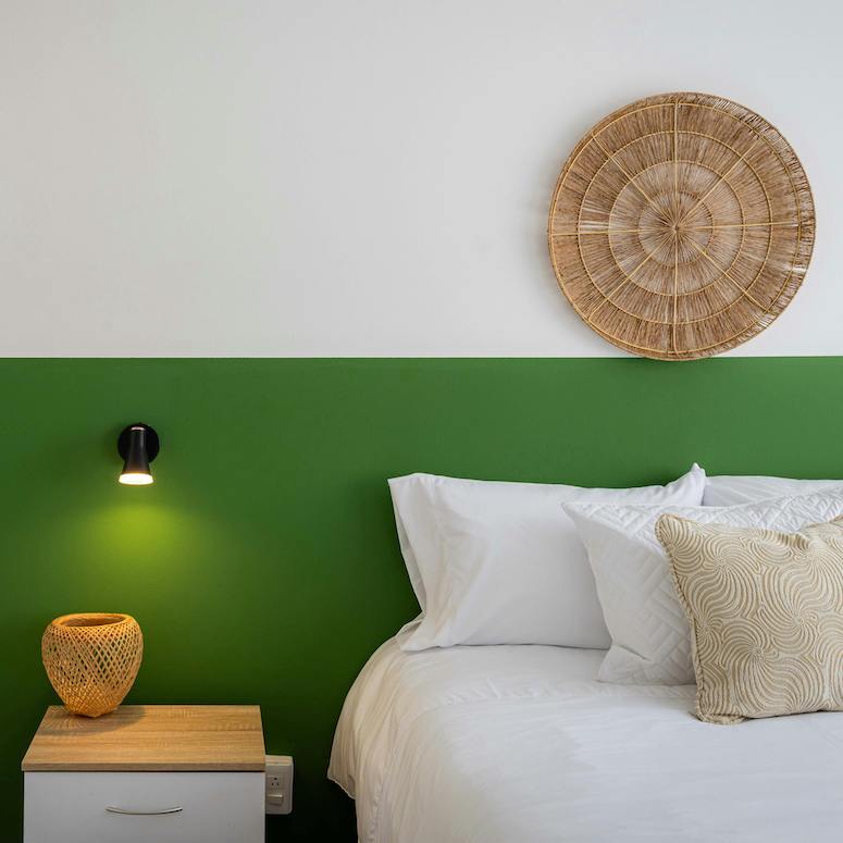 Wicker Plate over a bed against a block green colour wall
