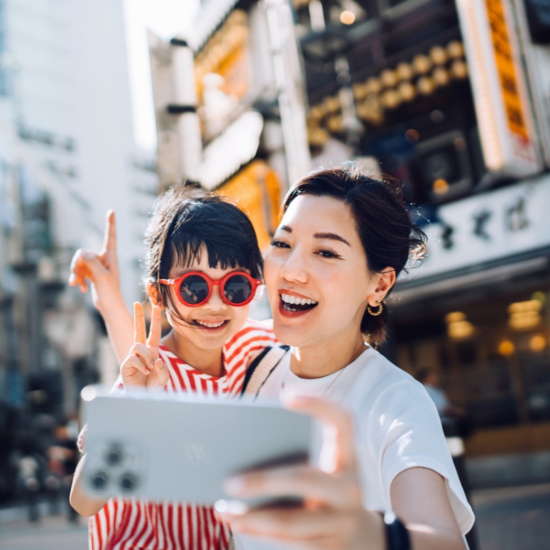 Mother taking a selfie with her lovely daughter with smartphone while exploring and sightseeing the city in Tokyo.