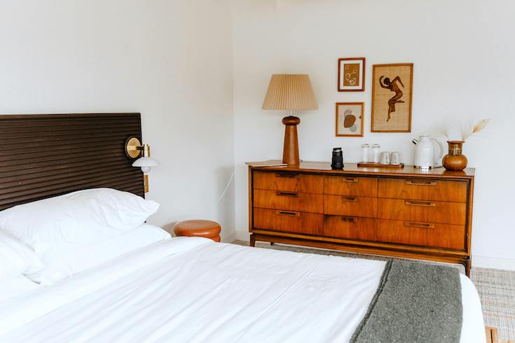 Interior Design in a chic bedroom with framed prints over a wooden credenza
