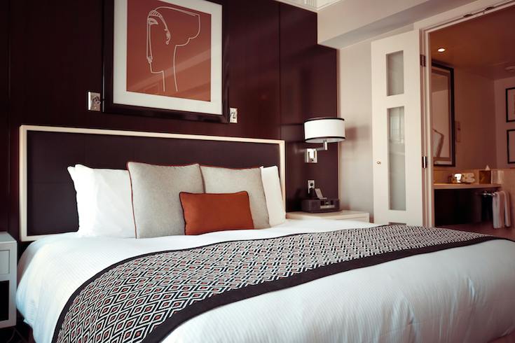 Black and Grey Bedspread on Bed and Pillow Dark wall in a bedroom with a large red framed print as bedroom wall decor
