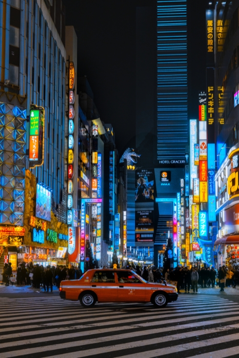 Tokyo Kabukicho entrance at night with taxi passing.